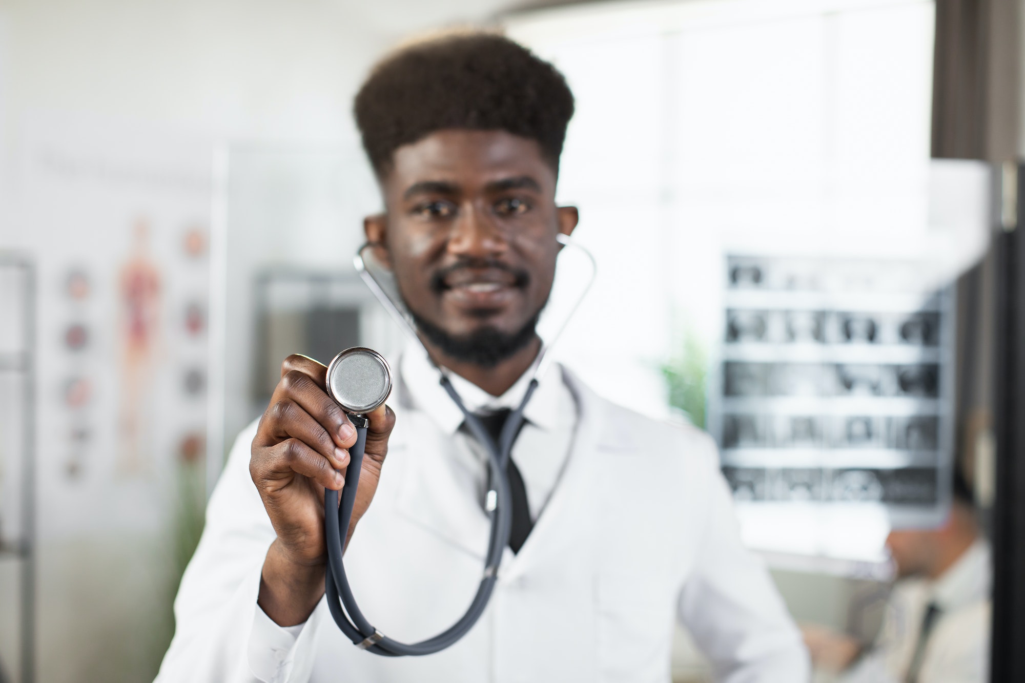 African doctor holding stethoscope and looking at camera